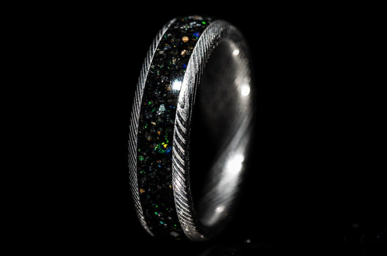 Custom Damascus steel sand inlay wedding band with textured edges and dark glittering inlay by Sangreal Rings
