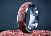Custom garnet titanium ring with reddish crystal inlay on a dark background