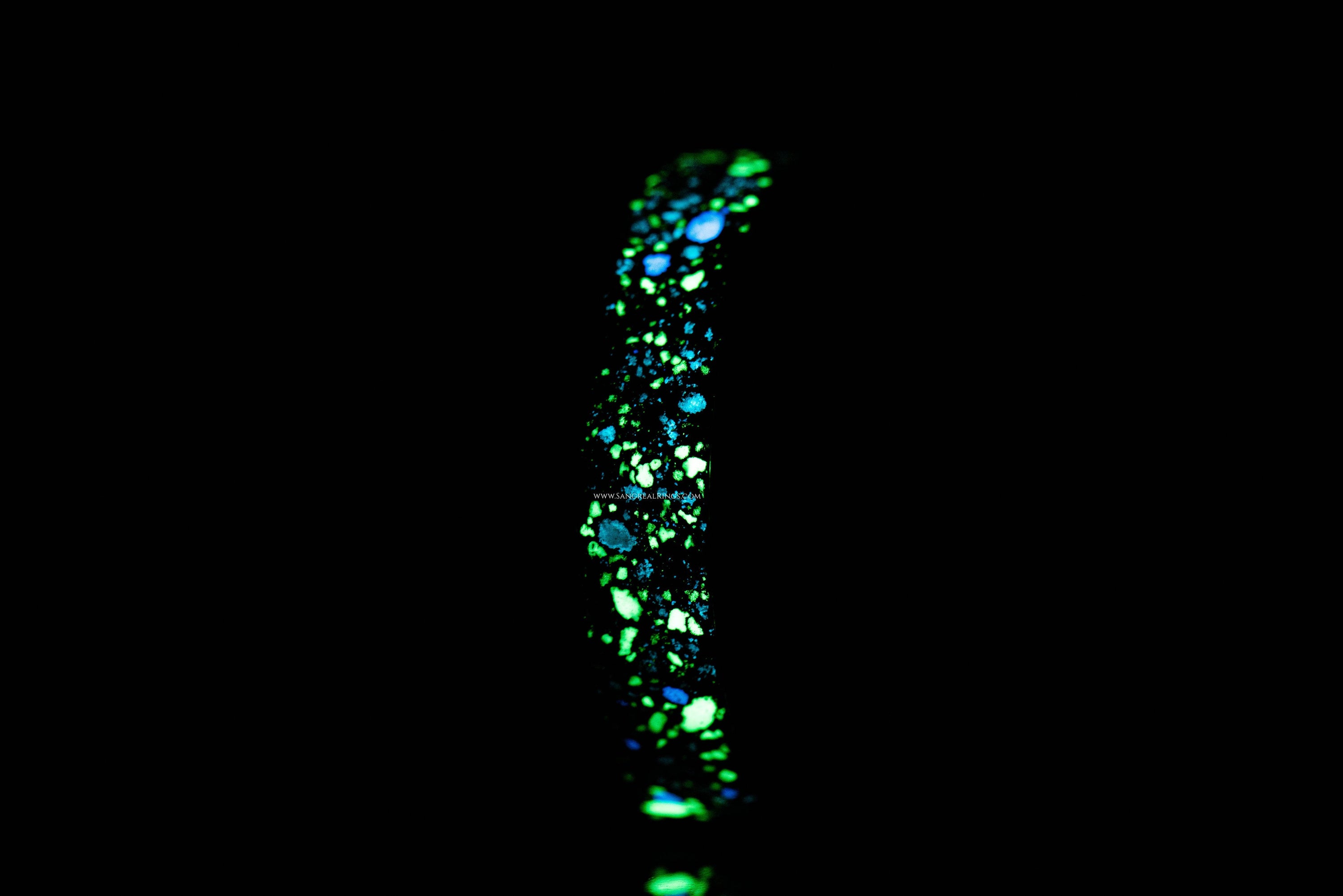 Custom glow in the dark ring by Sangreal Rings glowing with blue and green lights in darkness