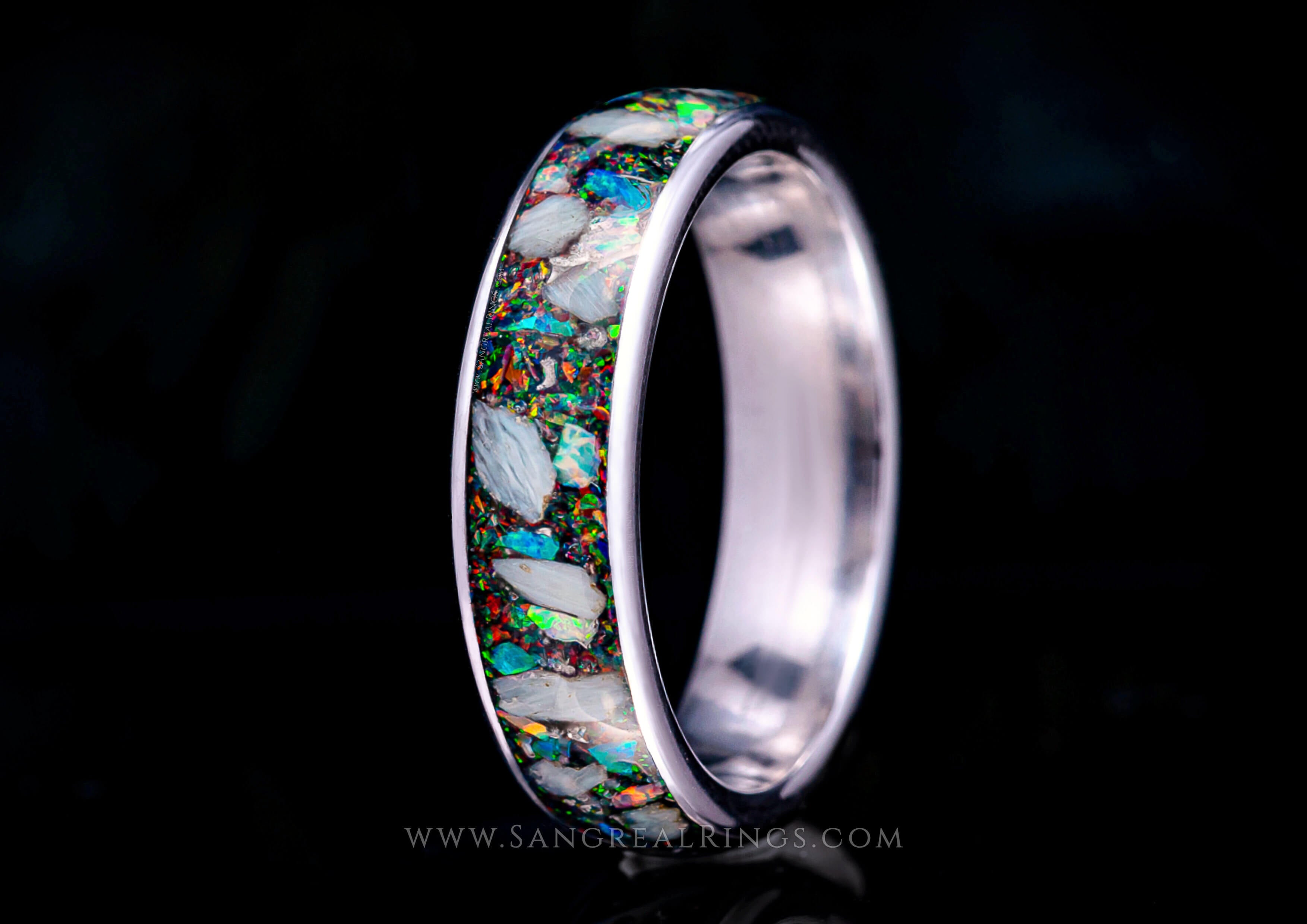 Custom titanium memorial keepsake ring with cremation ashes and multicolored opal inlay on a dark background, handcrafted in the UK by Sangreal Rings.