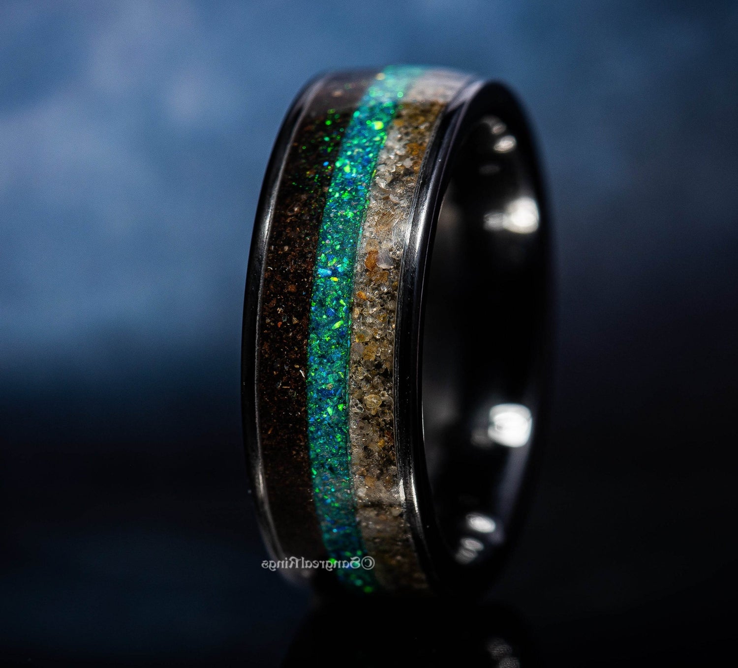 Sangreal Rings black ceramic sand ring with sparkling blue and sand-colored inlay on black background