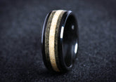 Black ceramic sand ring with contrasting light and dark sand inlay bands on dark background