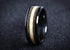 Black ceramic sand ring with contrasting light and dark sand inlay bands on dark background