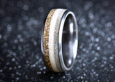 Close-up of a titanium sand ring by Sangreal Rings with layers of sand and metal against a dark background