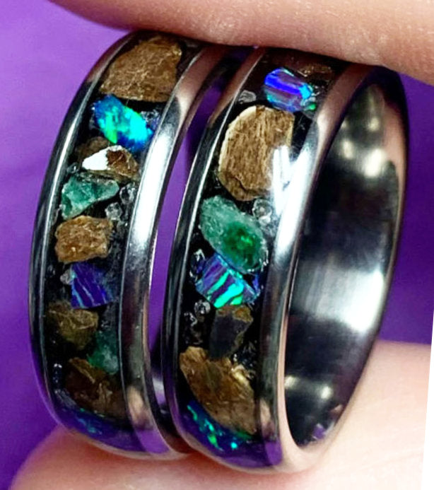 a set of handmade rings with a custom inlay of opal, fossil and emerald