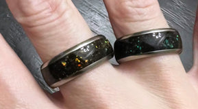 two sand rings with green and purple opal in titanium by sangrealrings