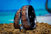 Black ceramic sand ring with embedded natural sand grains displayed on beach sand by Sangreal Rings