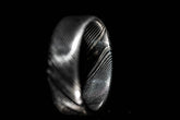 Handmade Damascus steel ring with intricate textured pattern on black background by Sangrealrings
