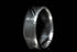 Close-up of a handmade Damascus steel ring with intricate layered patterns on black background