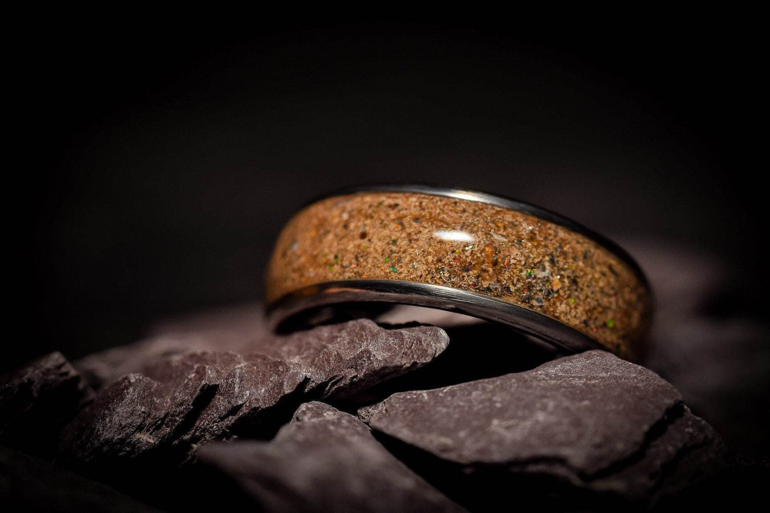 Sangrealrings opal dinosaur bone ring featuring a polished brown fossil inlay with silver band on dark stone background