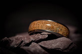 Sangrealrings opal dinosaur bone ring featuring a polished brown fossil inlay with silver band on dark stone background