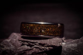 Opal megalodon tooth meteorite ring with glittering inlay resting on dark textured stones