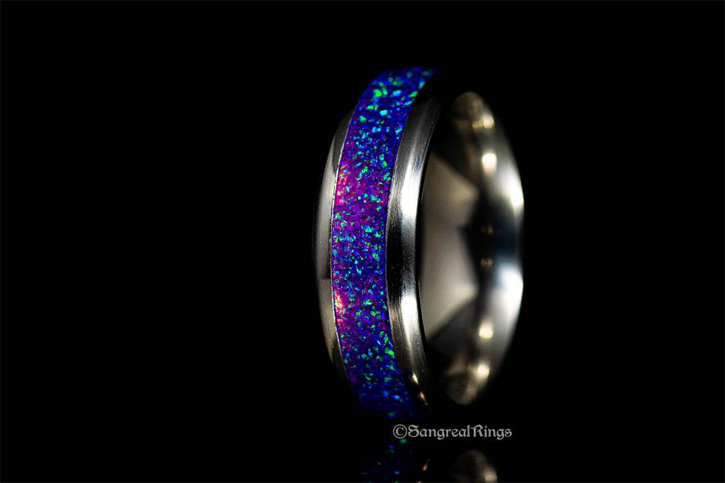 Close-up of a purple opal titanium ring with vibrant blue and purple inlay against a black background