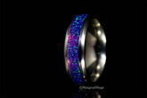 Close-up of a purple opal titanium ring with vibrant blue and purple inlay against a black background