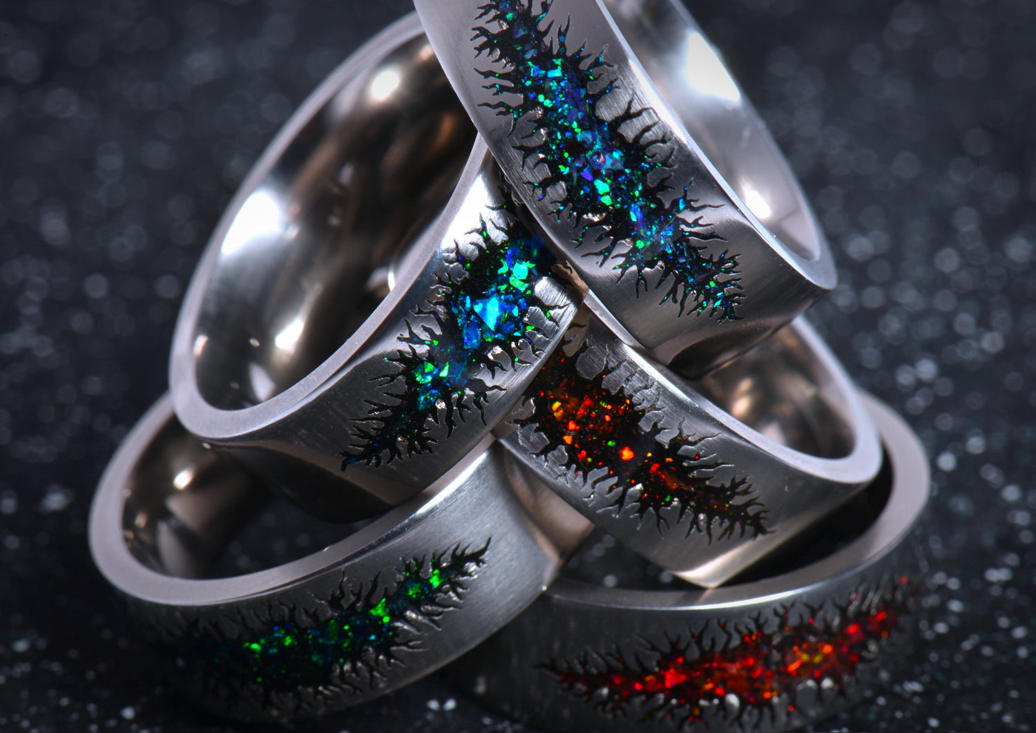 Custom cosmic scar ring collection featuring titanium bands with colorful shimmering starburst designs