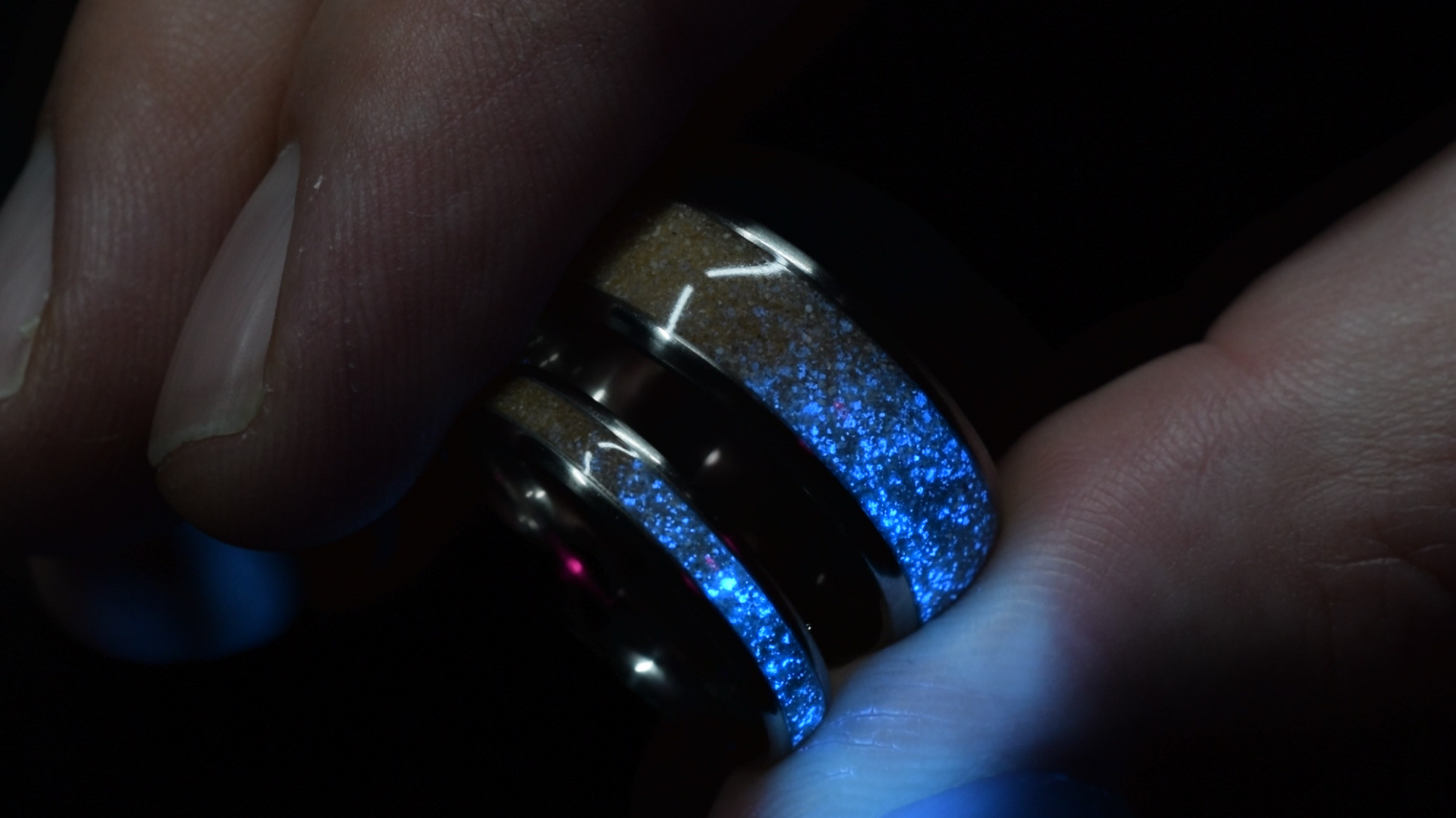 a set of glowing rings held between two fingers 