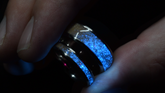 Custom titanium sand ring by Sangreal Rings glowing blue in dark with textured sand design
