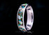 Custom titanium memorial keepsake ring with cremation ashes and multicolored opal inlay on a dark background, handcrafted in the UK by Sangreal Rings.