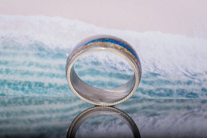 Close-up of Damascus steel sand ring with blue and gold sand details by Sangreal Rings