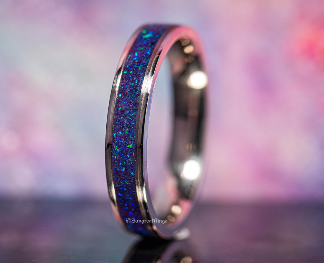 Close-up of a purple opal titanium ring with vibrant blue and purple inlay on a reflective surface