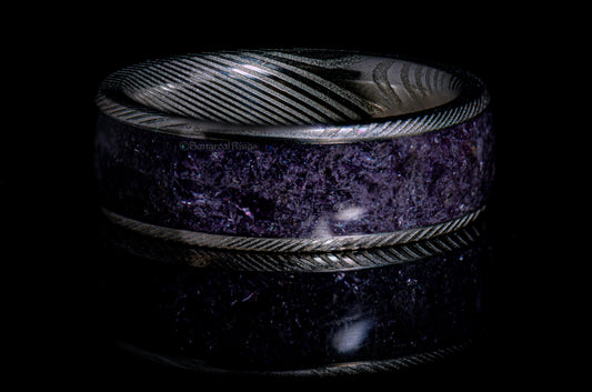 a damascus steel ring with a purple amethyst inlay on a dark background by sangrealrings