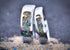 Two silver colored Titanium wedding rings with embedded colorful opal and stones on a sandy surface.