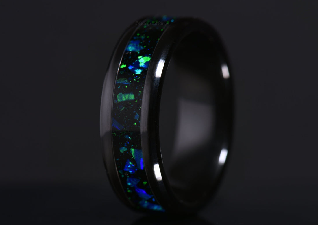 blue opal ring with green highlights in a black ceramic band on a dark background by sangrealrings