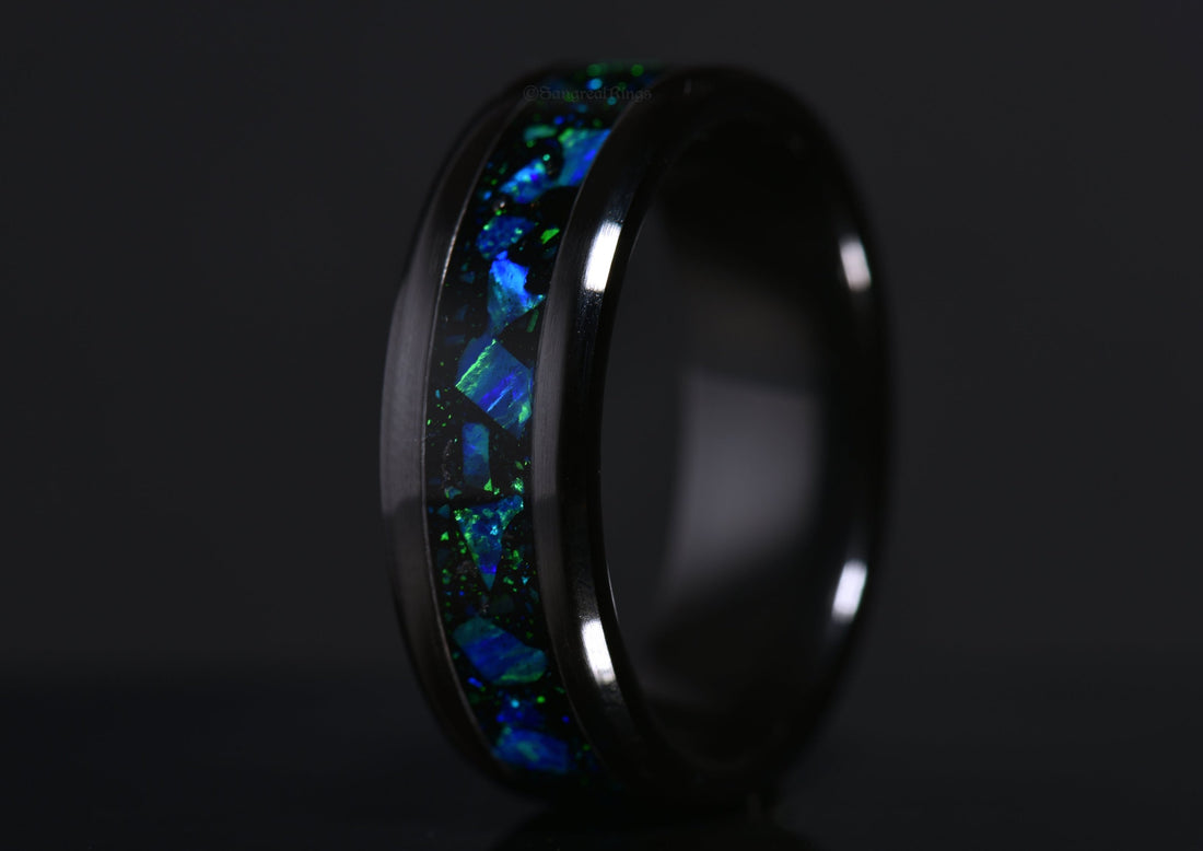 blue opal ring with green highlights in a black ceramic band on a dark background by sangrealrings