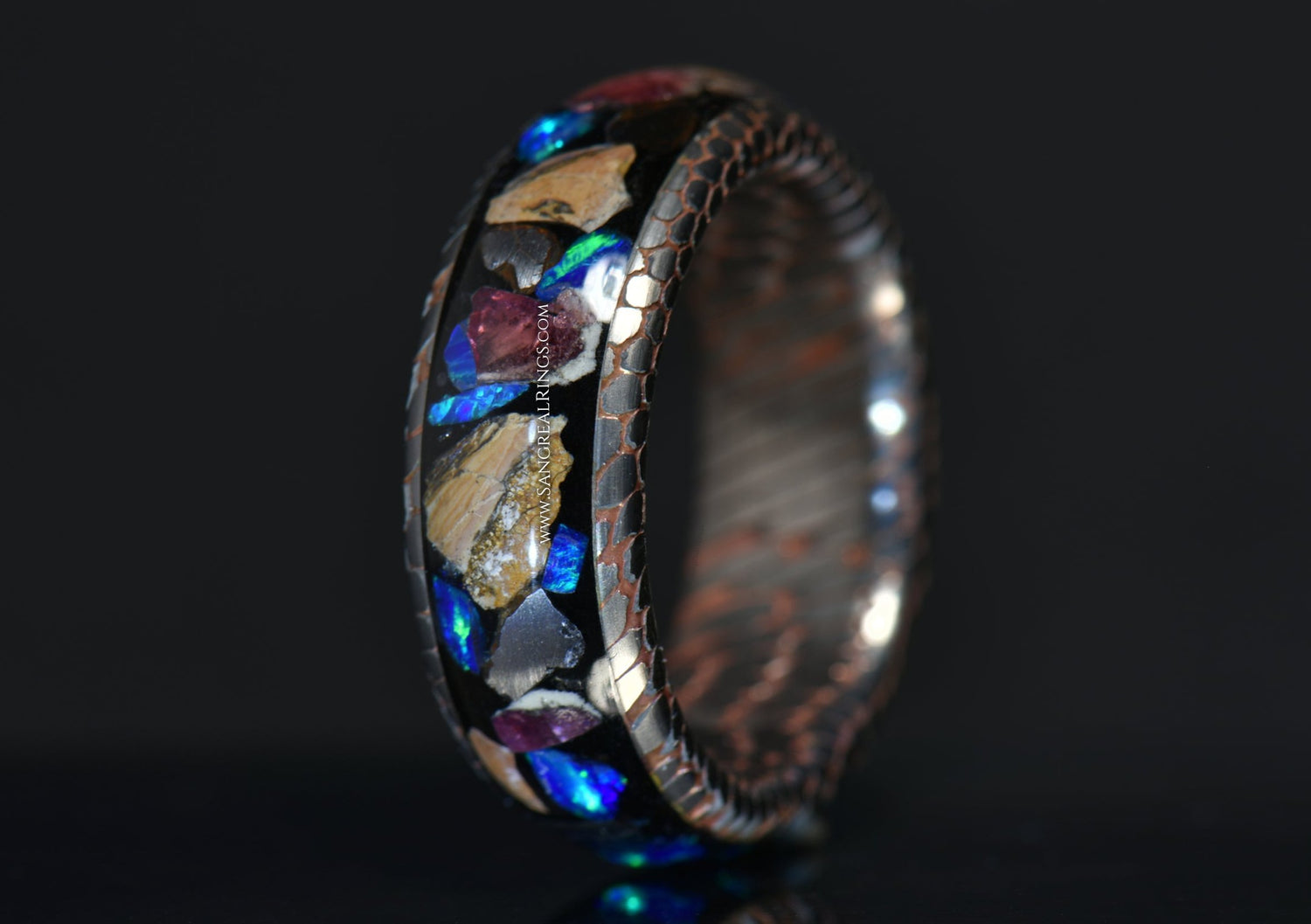 superconductor ring with raptor fossil blue opal and garnet shards made by sangrealrings on a dark background