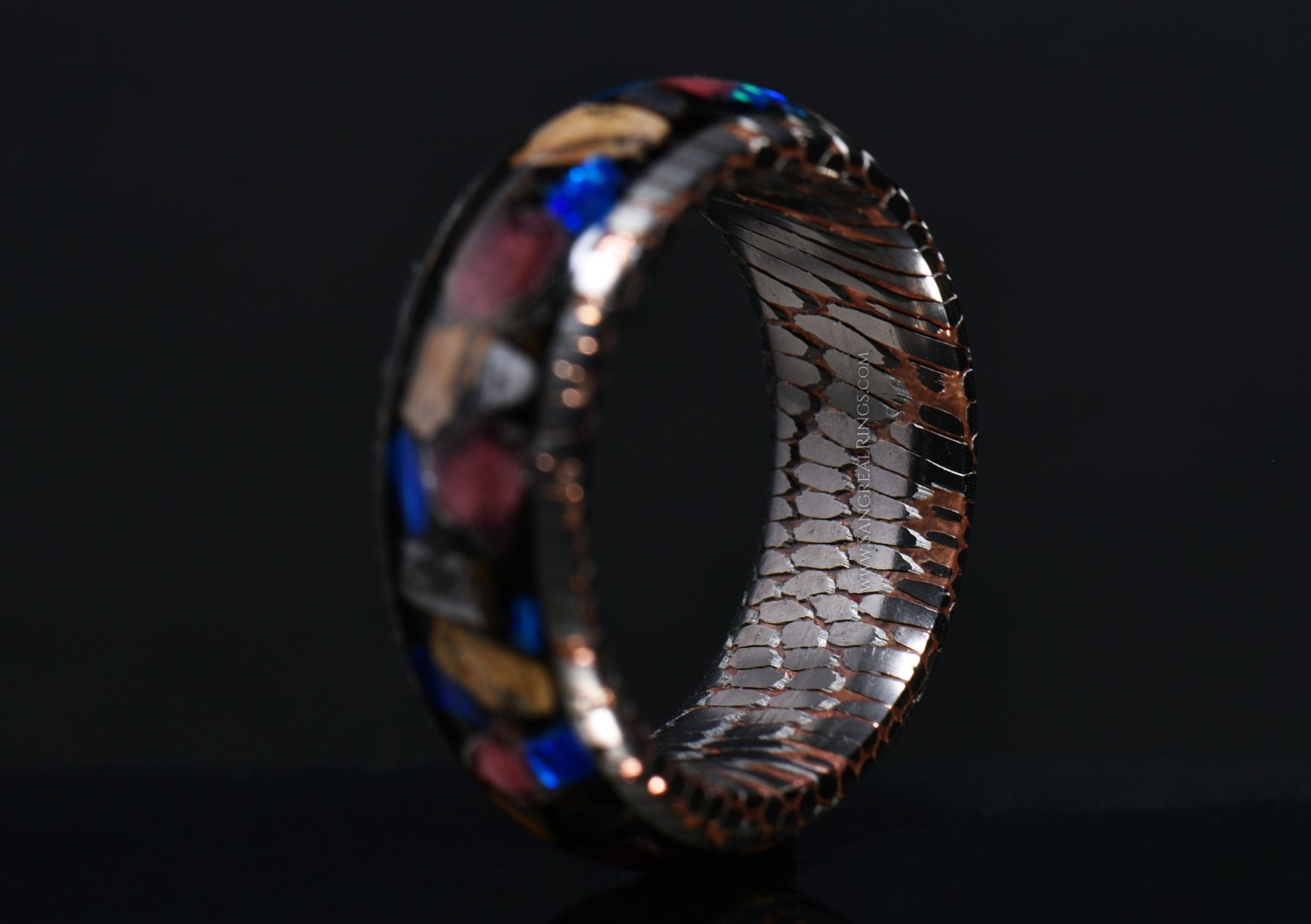 superconductor ring with raptor fossil blue opal and garnet shards made by sangrealrings on a dark background