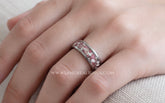 A close-up of a hand wearing a silver band ring with a textured, speckled pink ruby and white cremation ashes inlay. 