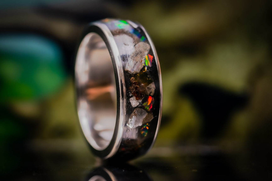 Titanium band with opal and stone resin inlay showing iridescent chips handmade alternative wedding ring