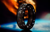 Black band opal and meteorite ring with colorful inlay on reflective surface and blurred background
