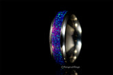 Close-up of a purple opal titanium ring with vibrant blue and purple inlay against a black background