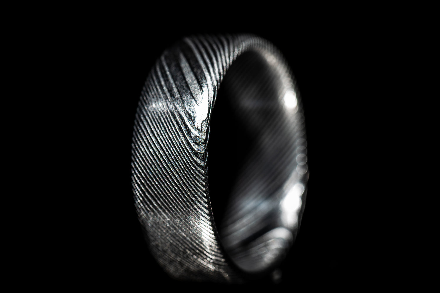 plain damascus steel ring on a dark background by sangrealrings